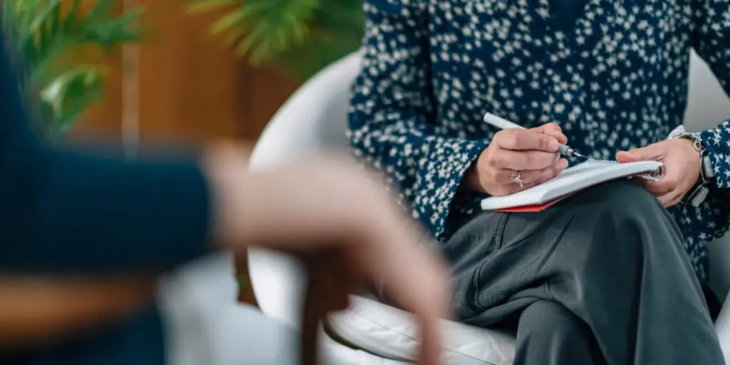 Person sitting on chair with notebook and pen